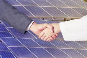 handshake in front of solar panels